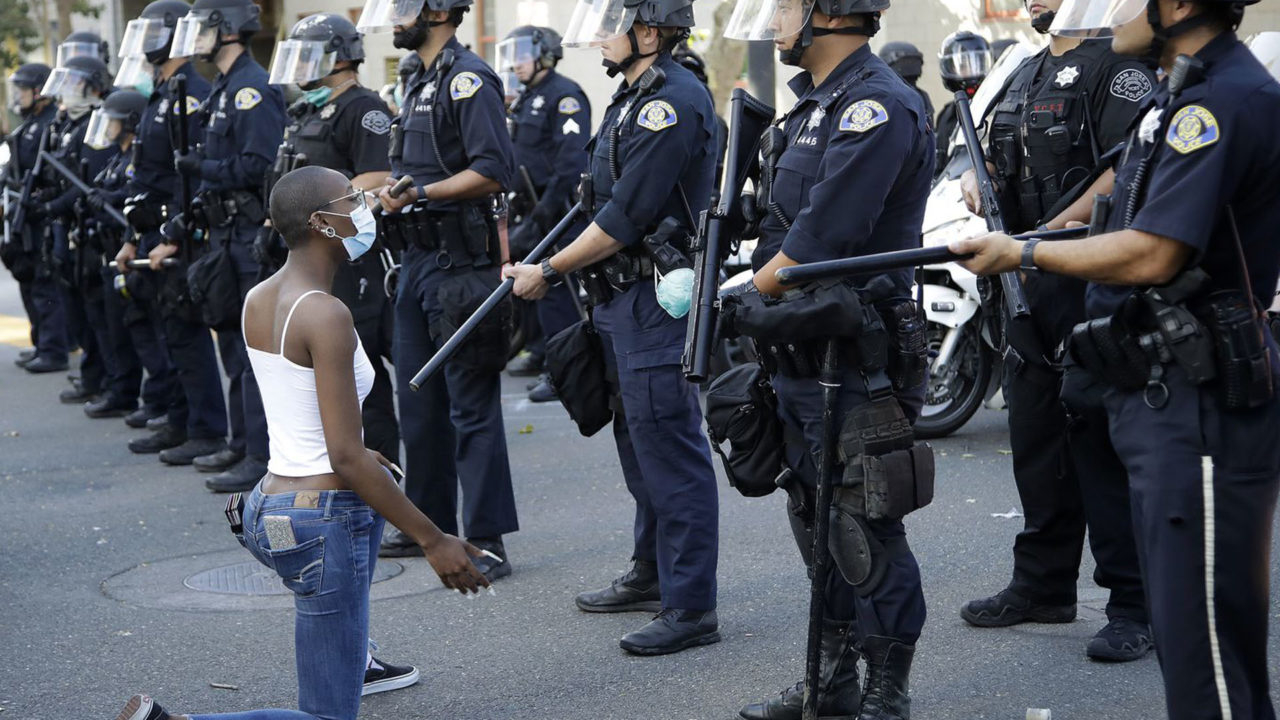 https://www.westafricanpilotnews.com/wp-content/uploads/2020/06/George-Floyd-Lady-kneels-in-Front-of-Police-06-02-20-1280x720.jpg