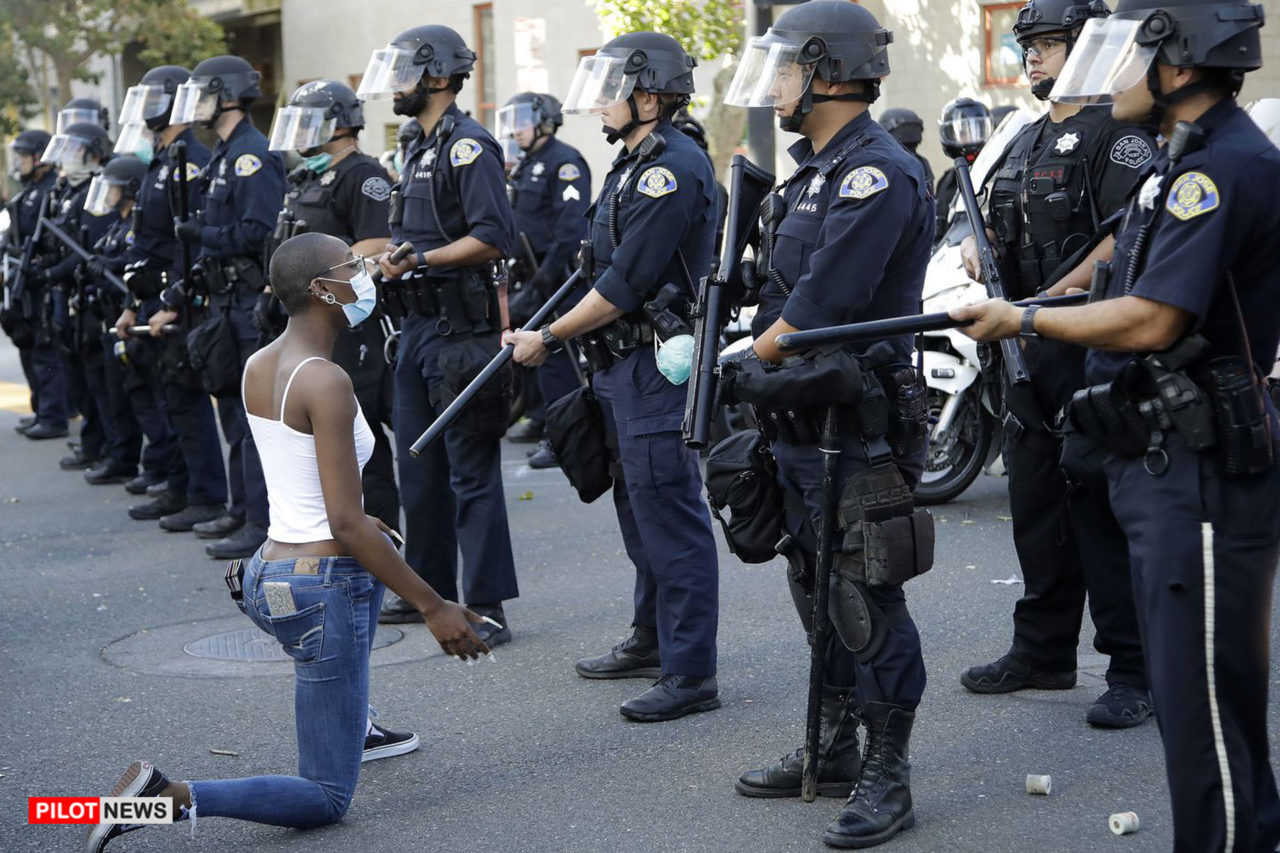 https://www.westafricanpilotnews.com/wp-content/uploads/2020/06/George-Floyd-Lady-kneels-in-Front-of-Police-06-02-20-1280x853.jpg